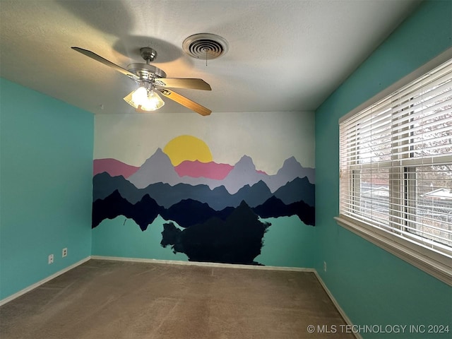 carpeted empty room with ceiling fan and a textured ceiling