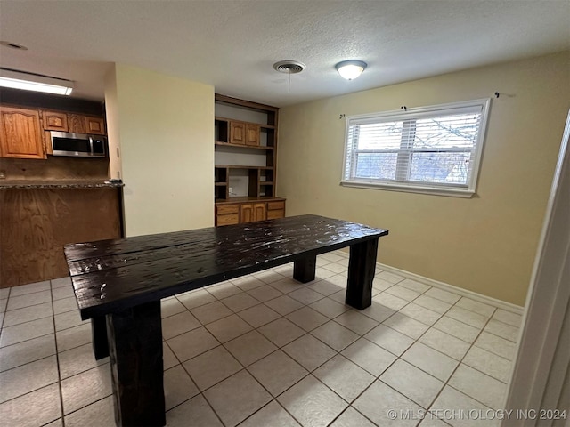 unfurnished office with light tile patterned flooring and a textured ceiling