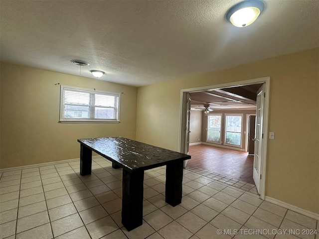 unfurnished dining area with a wealth of natural light, light tile patterned floors, a textured ceiling, and ceiling fan