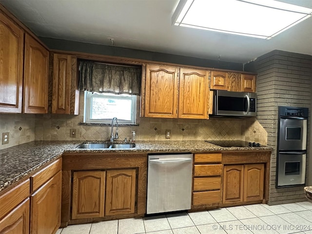 kitchen with tasteful backsplash, sink, light tile patterned floors, and stainless steel appliances