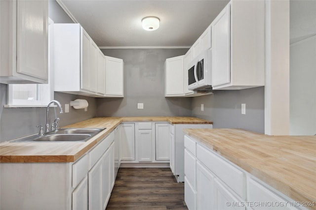 kitchen featuring wood counters, dark wood-type flooring, white cabinets, crown molding, and sink