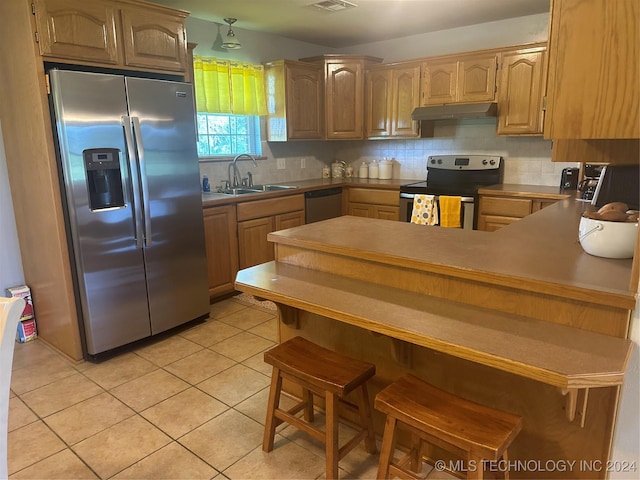 kitchen featuring sink, appliances with stainless steel finishes, tasteful backsplash, light tile patterned flooring, and kitchen peninsula