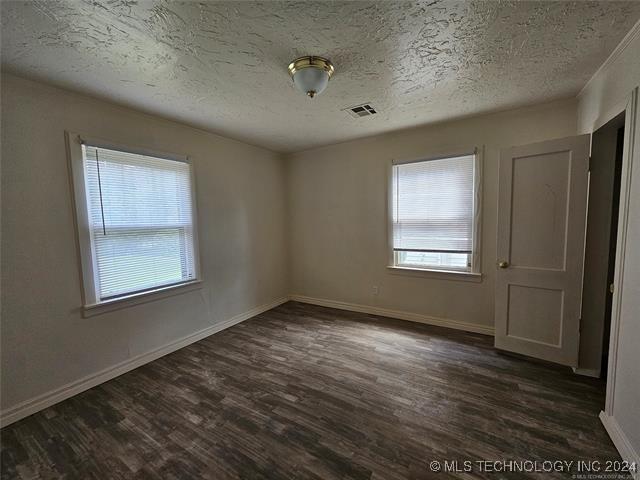 spare room featuring dark hardwood / wood-style flooring and a textured ceiling