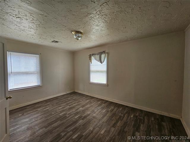 unfurnished room with dark hardwood / wood-style flooring and a textured ceiling