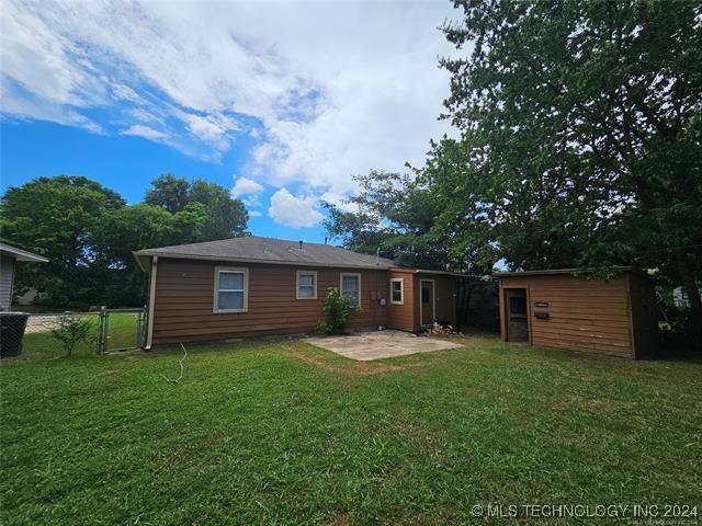 rear view of house featuring a patio area, a yard, and a storage shed