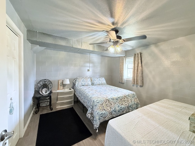 bedroom featuring a textured ceiling, a closet, light hardwood / wood-style flooring, and ceiling fan