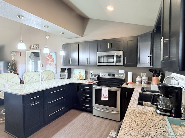 kitchen featuring lofted ceiling, hanging light fixtures, stainless steel appliances, light stone counters, and kitchen peninsula