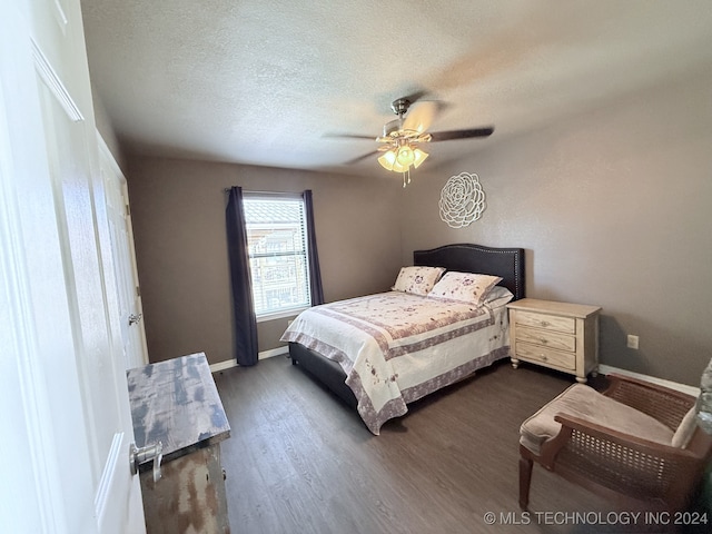 bedroom with ceiling fan, dark hardwood / wood-style flooring, and a textured ceiling