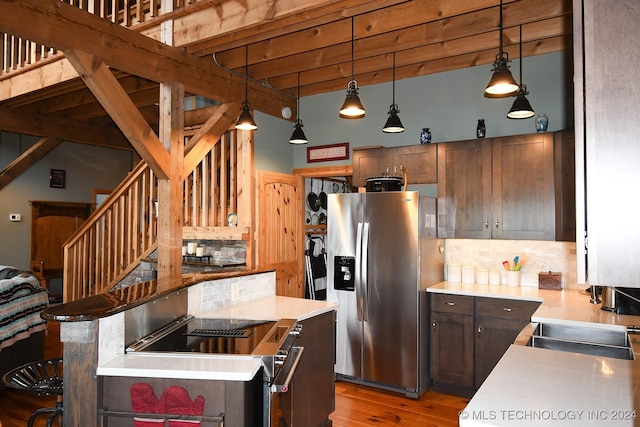 kitchen featuring beam ceiling, stainless steel appliances, hardwood / wood-style floors, decorative light fixtures, and decorative backsplash