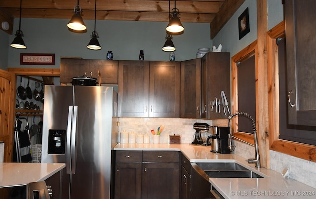 kitchen with pendant lighting, stainless steel fridge, sink, and backsplash