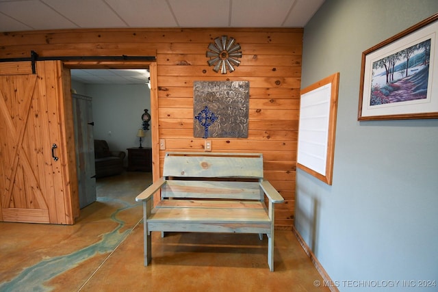 interior space with a barn door and a drop ceiling