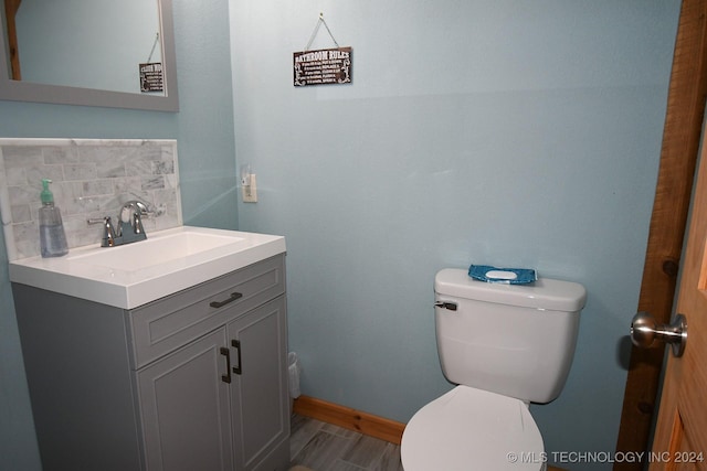 bathroom featuring decorative backsplash, wood-type flooring, vanity, and toilet