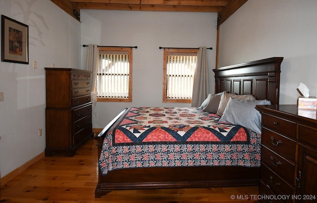 bedroom featuring beam ceiling and dark hardwood / wood-style flooring