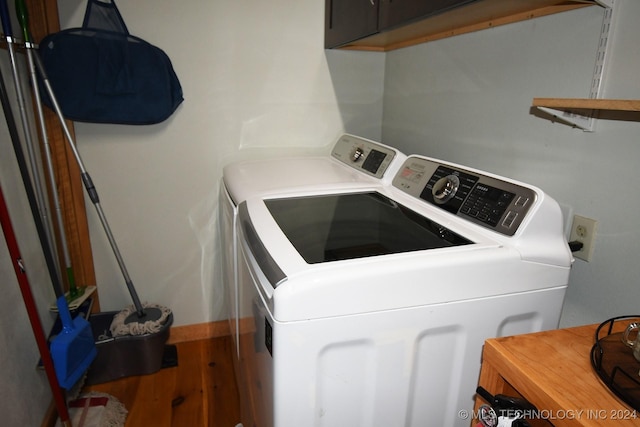 washroom featuring hardwood / wood-style flooring, washer and dryer, and cabinets