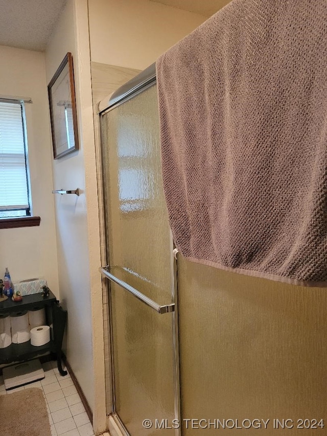 bathroom with tile patterned flooring and a shower with shower door