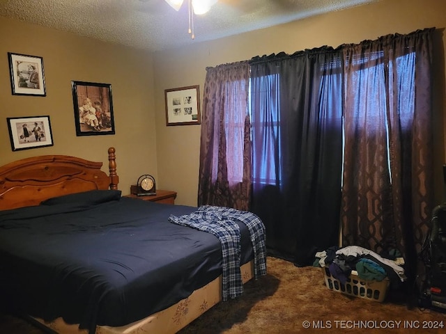 bedroom with ceiling fan, carpet floors, and a textured ceiling