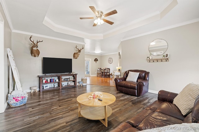 living room featuring dark wood-type flooring, ornamental molding, a raised ceiling, and ceiling fan