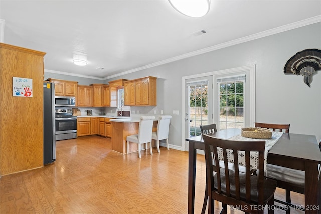 kitchen with a kitchen bar, kitchen peninsula, stainless steel appliances, ornamental molding, and light hardwood / wood-style flooring