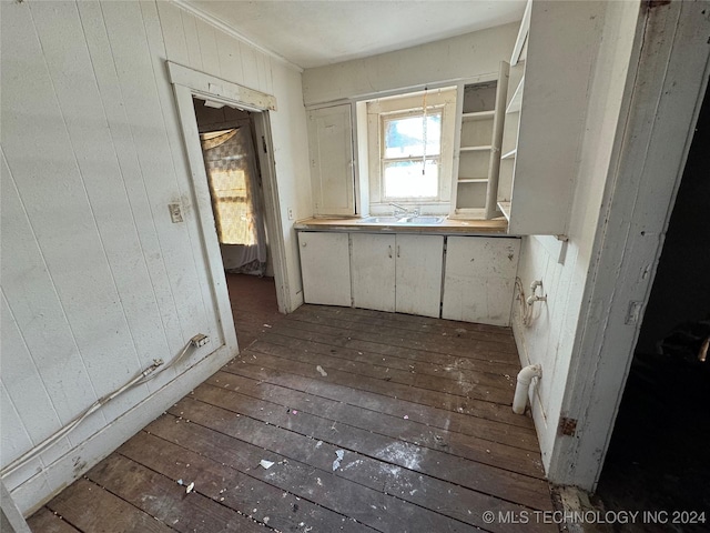 interior space with hardwood / wood-style flooring, sink, and wooden walls