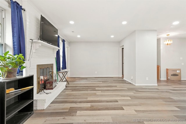 living room featuring a fireplace, a chandelier, and light hardwood / wood-style flooring