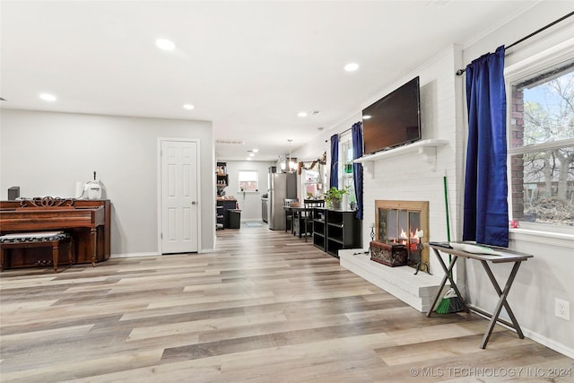 interior space featuring a brick fireplace, crown molding, and light wood-type flooring