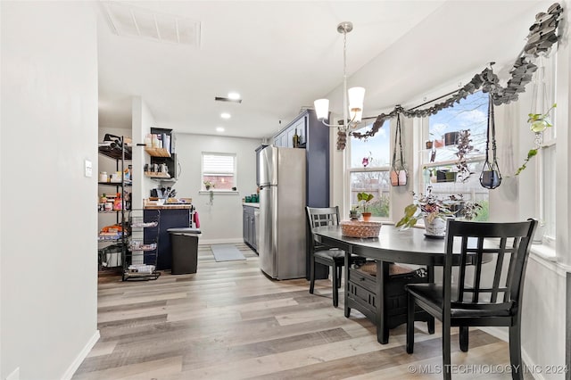 dining area with light hardwood / wood-style floors and a notable chandelier