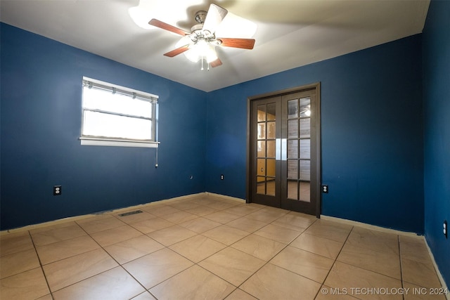 tiled empty room featuring ceiling fan and french doors