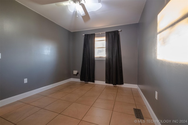 tiled empty room with ceiling fan and vaulted ceiling