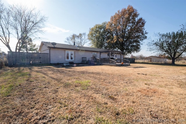 rear view of property featuring a wooden deck and a lawn