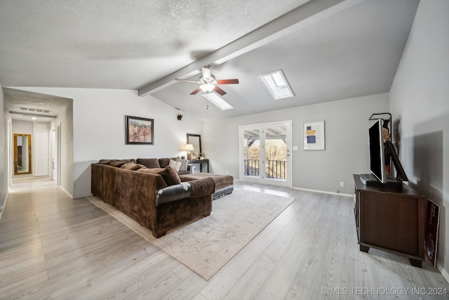 living room featuring lofted ceiling with beams, ceiling fan, light wood-type flooring, and a textured ceiling