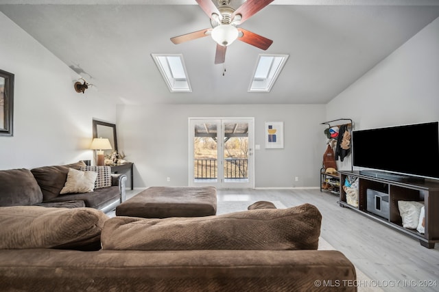 living room with vaulted ceiling with skylight, ceiling fan, and light hardwood / wood-style flooring