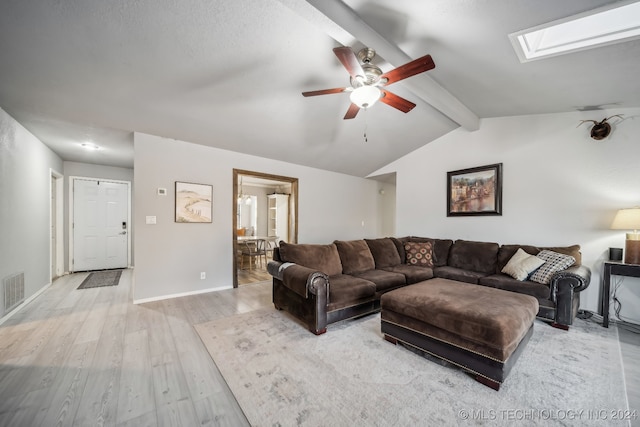 living room featuring light hardwood / wood-style floors, ceiling fan, and vaulted ceiling with skylight