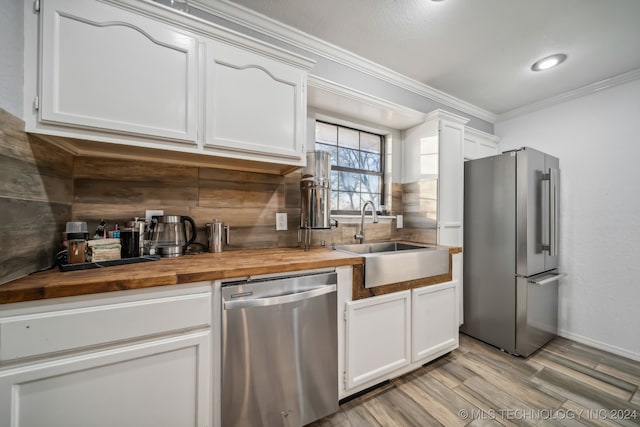 kitchen with wooden counters, stainless steel appliances, white cabinets, and sink