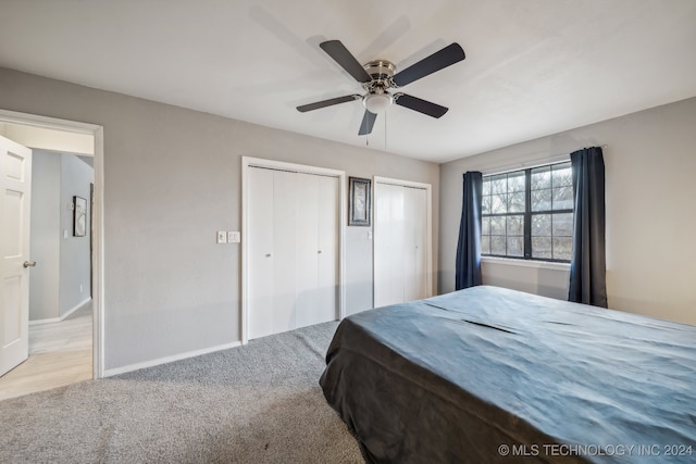 carpeted bedroom with ceiling fan and multiple closets