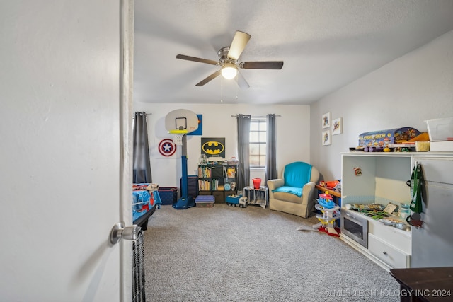 recreation room with ceiling fan, carpet, and a textured ceiling