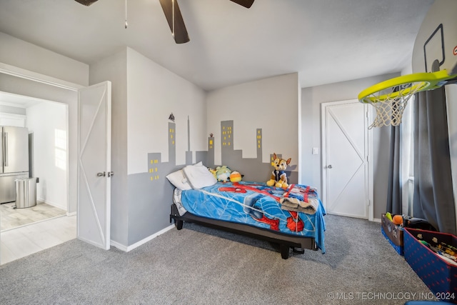 carpeted bedroom with ceiling fan and stainless steel fridge