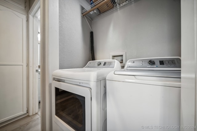 clothes washing area with independent washer and dryer and light wood-type flooring