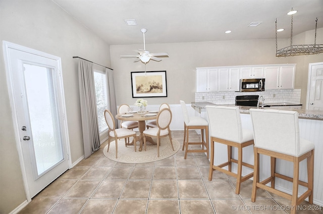 kitchen with ceiling fan, light tile patterned floors, tasteful backsplash, a breakfast bar, and white cabinets