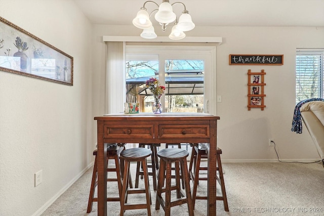 dining room with light carpet and a chandelier