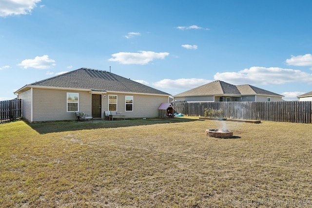 back of house with a yard and a fire pit