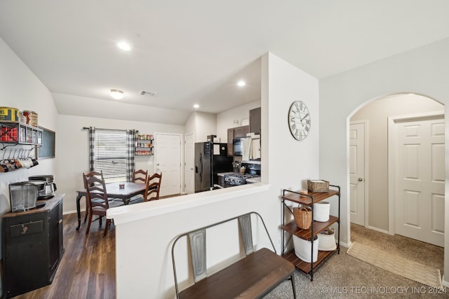 kitchen with vaulted ceiling, dark hardwood / wood-style flooring, kitchen peninsula, and black appliances