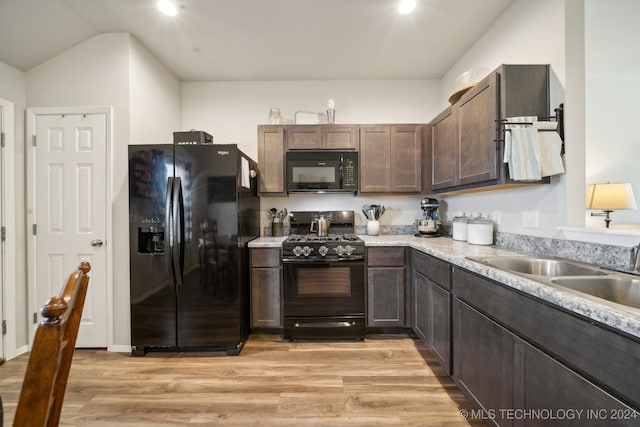 kitchen featuring dark brown cabinetry, black appliances, sink, vaulted ceiling, and light hardwood / wood-style flooring