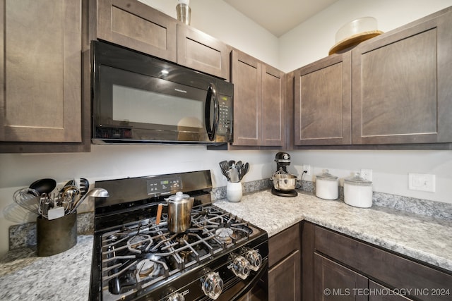 kitchen with dark brown cabinets, light stone counters, and black appliances