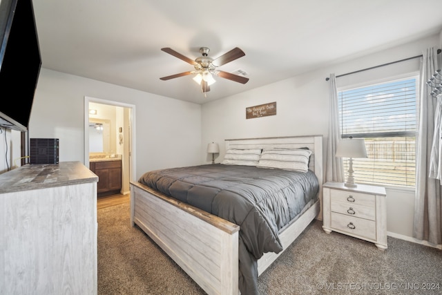 bedroom with ceiling fan, multiple windows, dark carpet, and ensuite bathroom