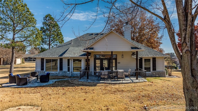 rear view of property featuring a lawn, french doors, and a patio