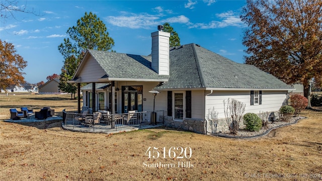 back of house with a lawn and covered porch