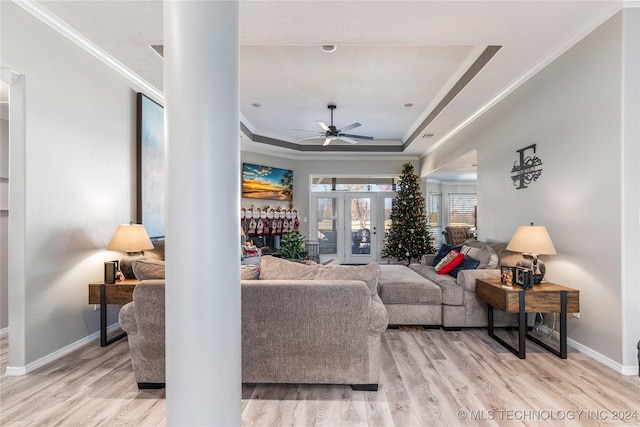 living room featuring light hardwood / wood-style floors, a raised ceiling, and ornamental molding