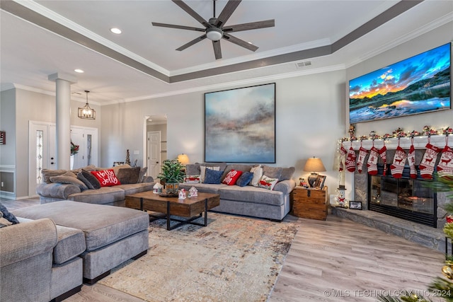 living room featuring hardwood / wood-style floors, ceiling fan, ornamental molding, and a fireplace