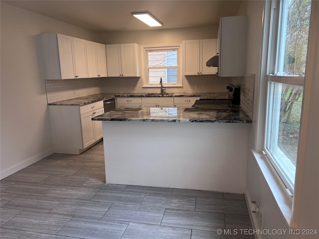 kitchen with white cabinetry, electric range, range hood, kitchen peninsula, and dark stone countertops