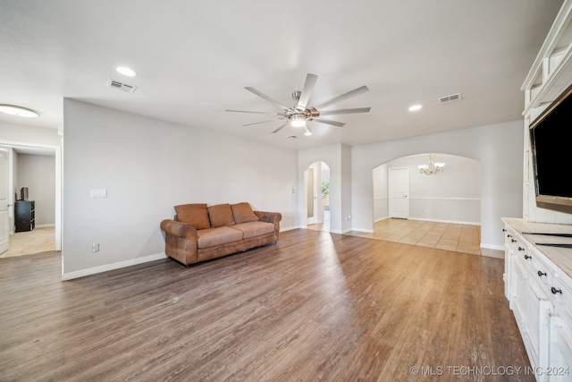 living room with wood-type flooring and ceiling fan with notable chandelier